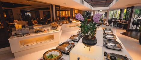 A buffet setup with various food stations and a central floral arrangement.
