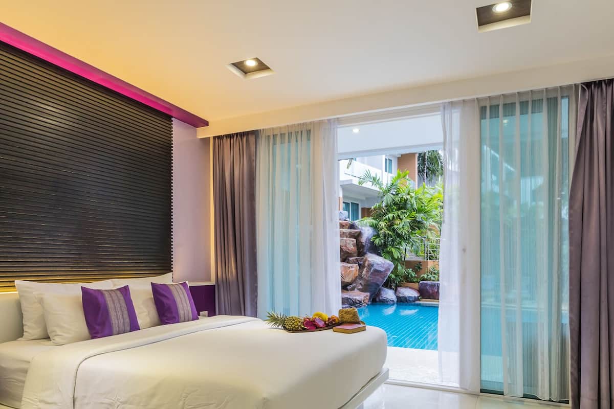 Habitación de hotel con cama, vista a una piscina al aire libre y balcón con cortinas.