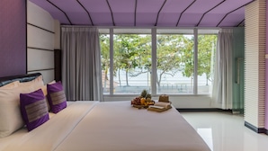 A modern hotel room with a large bed, a view of the sea, and a beach visible through the windows. - The L Resort (Krabi)