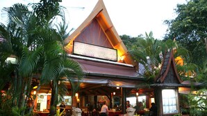 A restaurant with a traditional architectural style, featuring a prominent sign and outdoor seating surrounded by lush greenery. - The L Resort (Krabi)