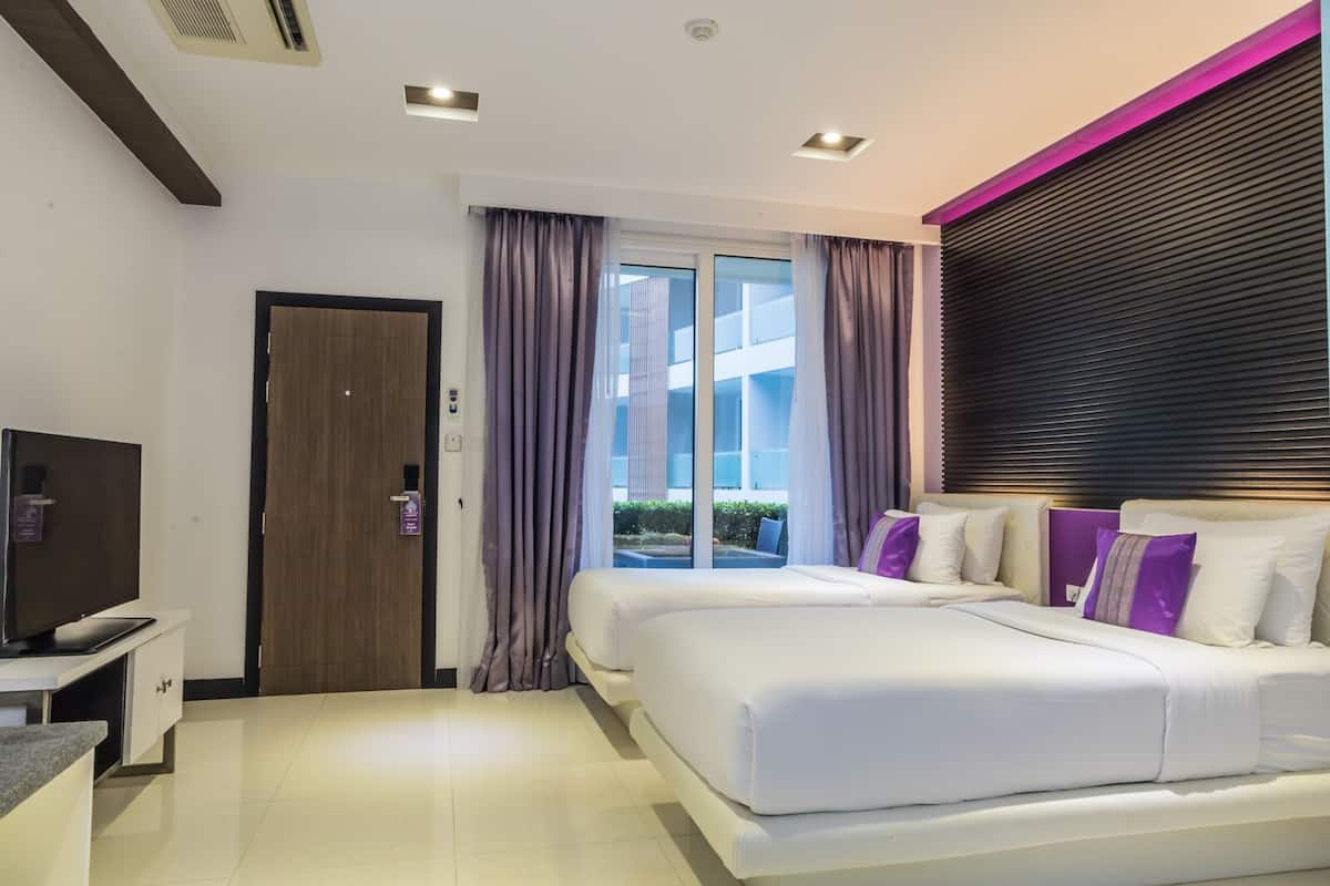 Habitación de hotel moderna con una cama grande, un televisor de pantalla plana y vistas al exterior a través de una puerta de cristal.