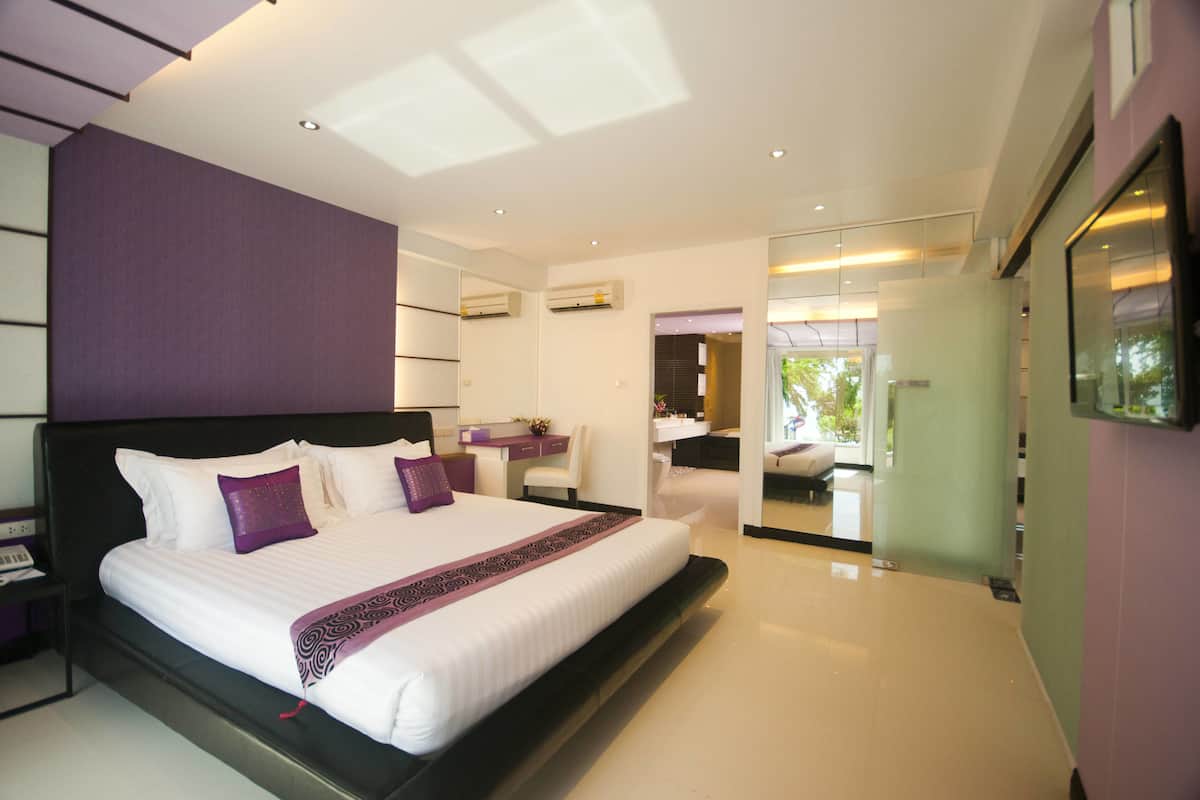 Una habitación de hotel moderna con una cama grande, un escritorio y un baño visible a través de una puerta de cristal.