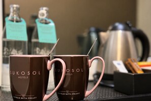 Twee bruine mokken met roze handgrepen en de tekst 'SUKOSOL HOTELS' op een tafel.