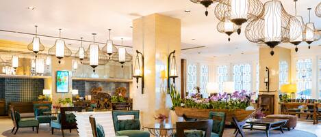 A spacious lobby with multiple seating areas, a reception desk, and decorative lighting fixtures.