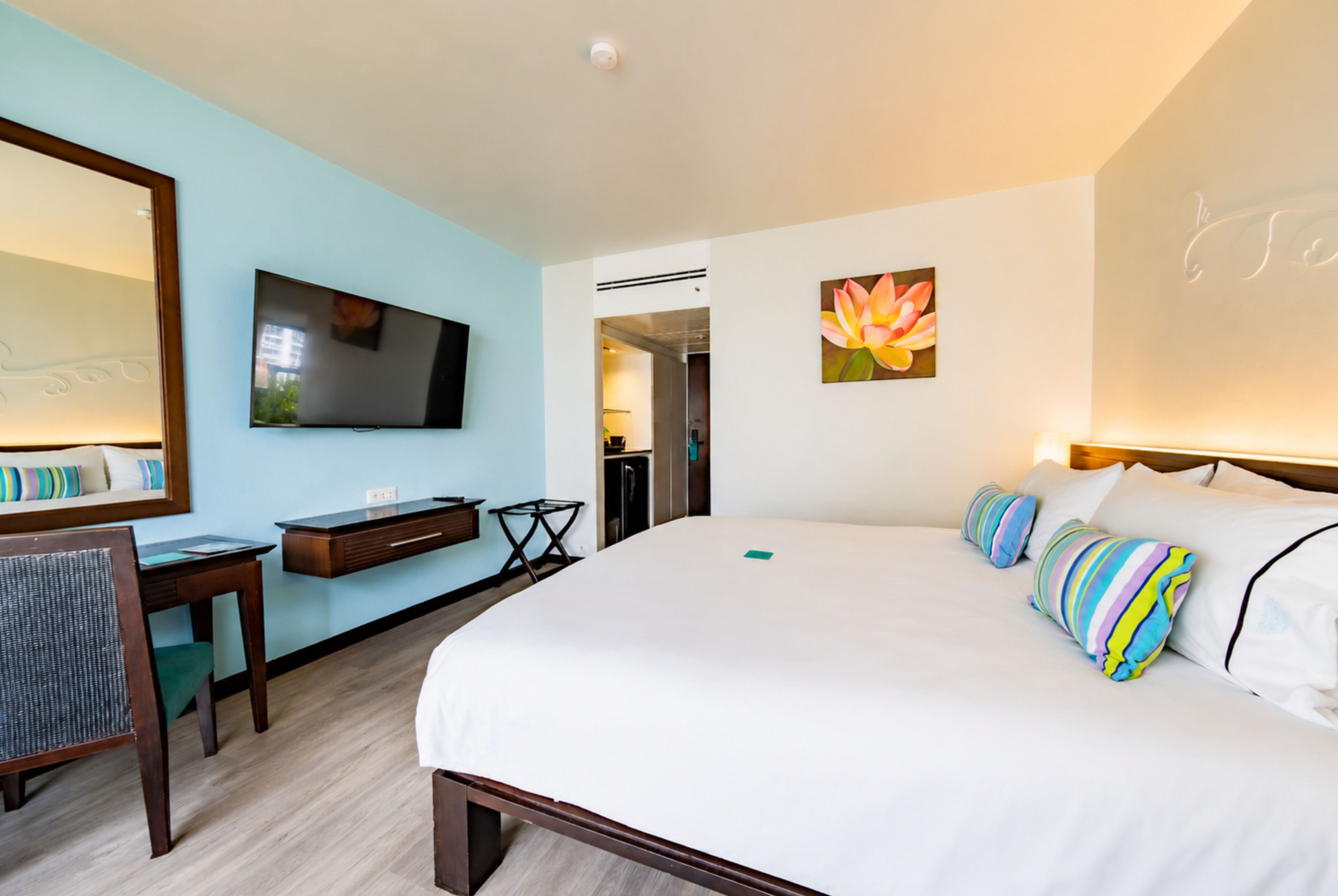 Une chambre d’hôtel avec un lit, un bureau, une chaise, une télévision et un tableau au mur.