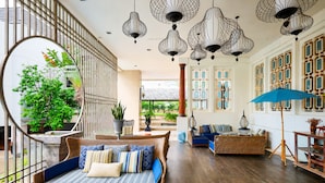 A spacious living area with a large sofa, a round mirror, and a dining table. - The Bayview Hotel Pattaya (Pattaya)
