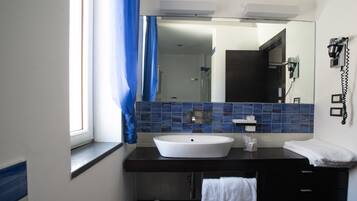 A bathroom with a white sink, dark countertop, and a mirror above it.