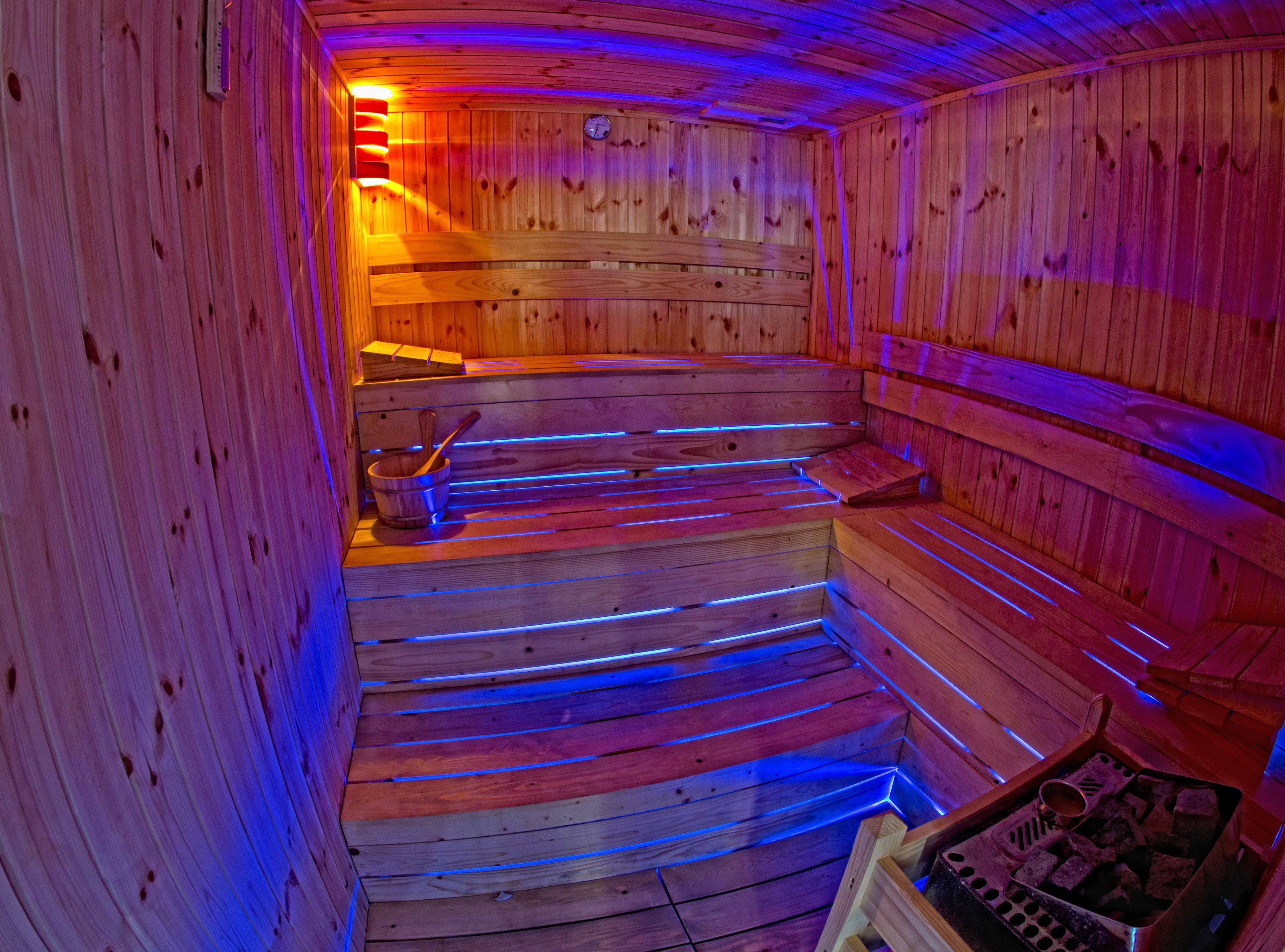 Eine Sauna mit Holzbänken und einer Holzverkleidung sowie einer Uhr.