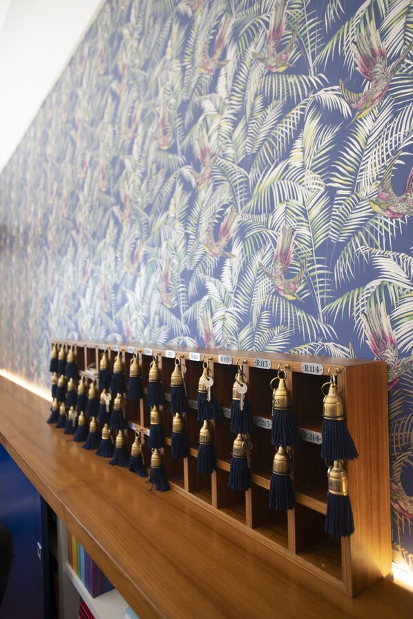 Une étagère en bois avec des clés suspendues et un mur à motifs en arrière-plan.