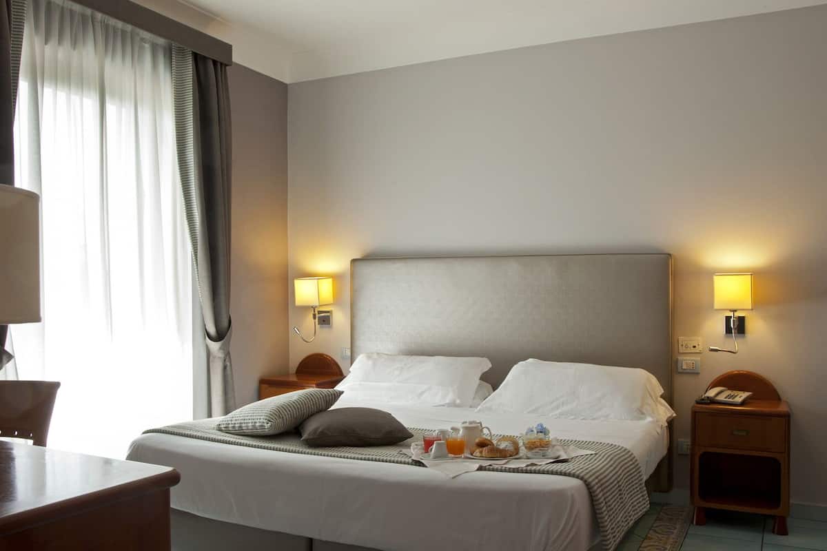 Une chambre d’hôtel avec un grand lit, deux tables de chevet, un bureau et une chaise.