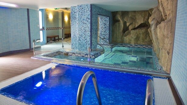 Ein hallenbad mit klarem Wasser, einer Steinwand und Fliesenwänden.