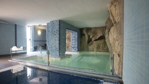 Ein Schwimmbecken mit einer Felswand und gefliesten Wänden.