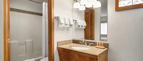 Un bagno con un mobile vanitario in legno, un lavandino, uno specchio e una doccia.