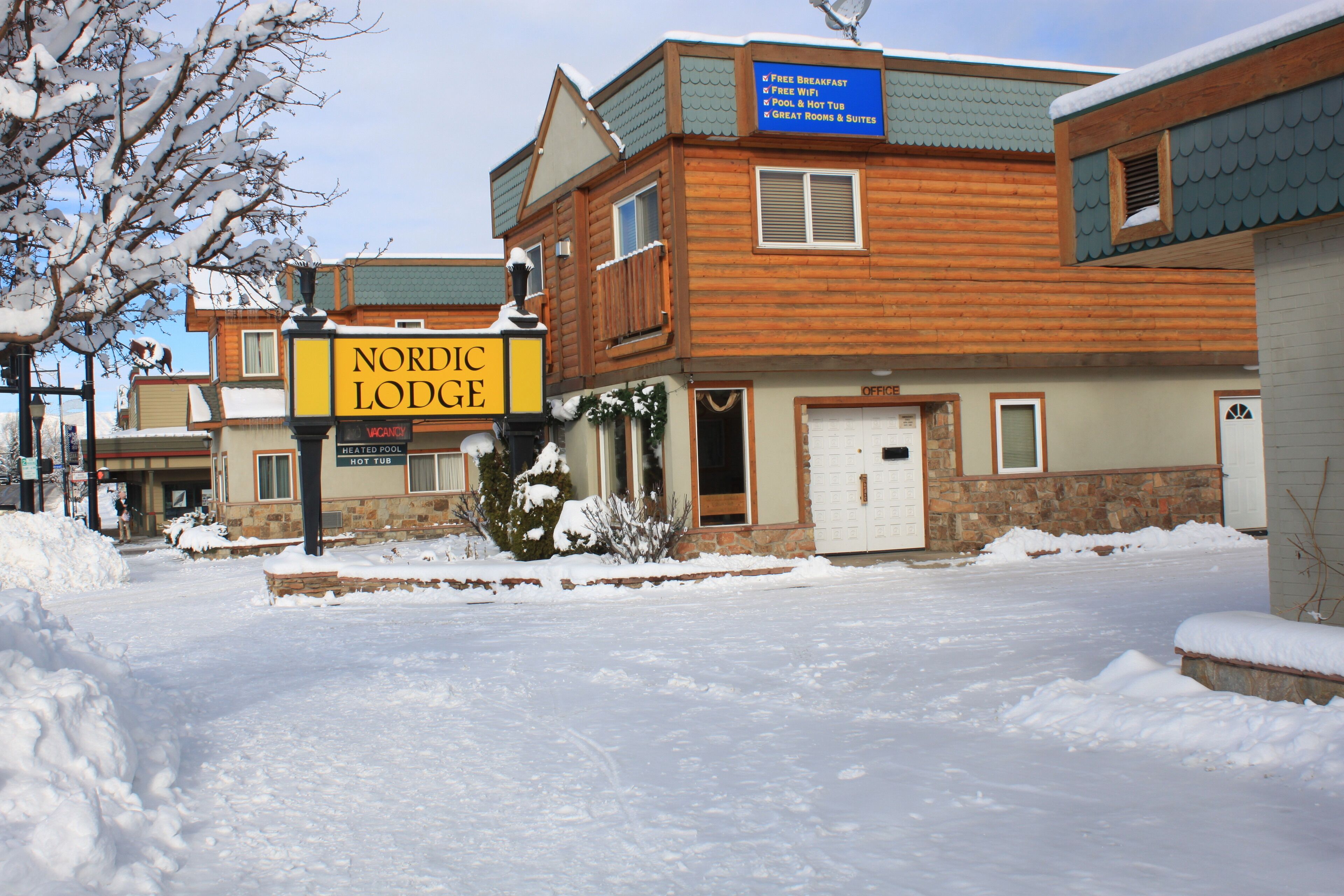 A Nordic Lodge building with a signboard, wooden exterior, and snow-covered surroundings.