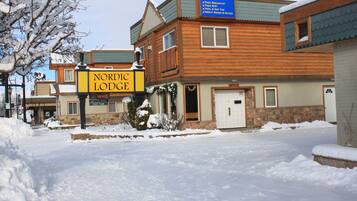 A Nordic Lodge building with a signboard, wooden exterior, and snow-covered surroundings.