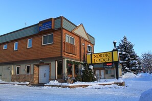 Ein hölzernes Gebäude mit einem Schild, auf dem „Nordic Lodge“ steht, und Auflistungen der Annehmlichkeiten über dem Eingang.