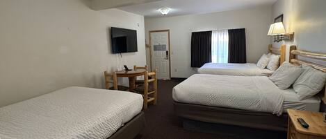 A hotel room with two beds, a desk, a TV, and a lamp.