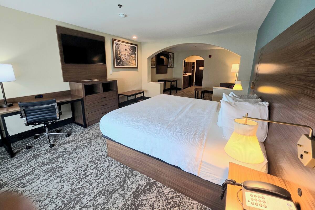 Una habitación de hotel con una cama grande, un escritorio con una silla, un televisor y una mesita.