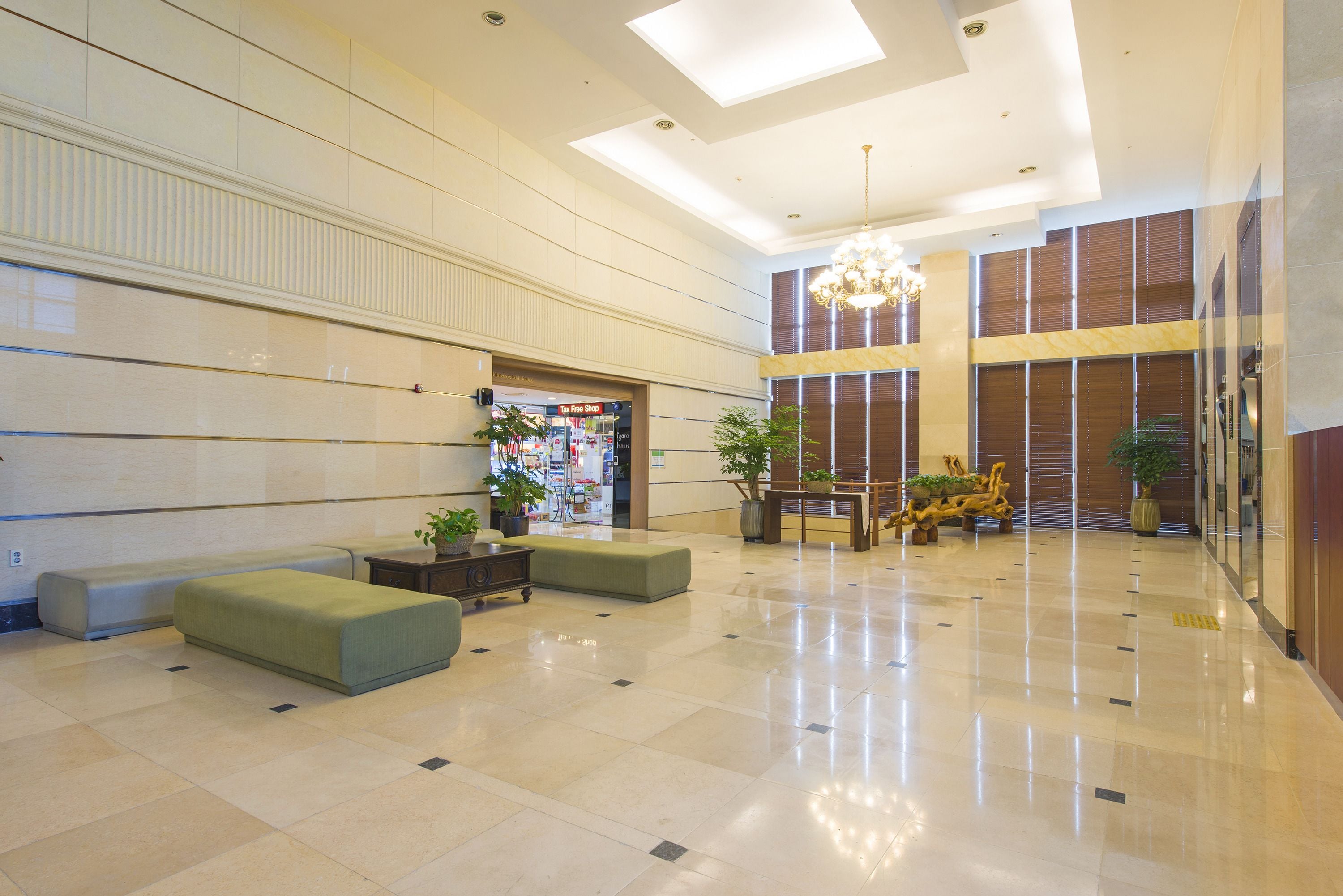 A spacious lobby with a high ceiling, a central seating area, and a reception desk.