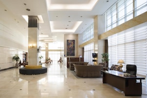 A spacious lobby with a reception desk, seating area, and a large window providing natural light.