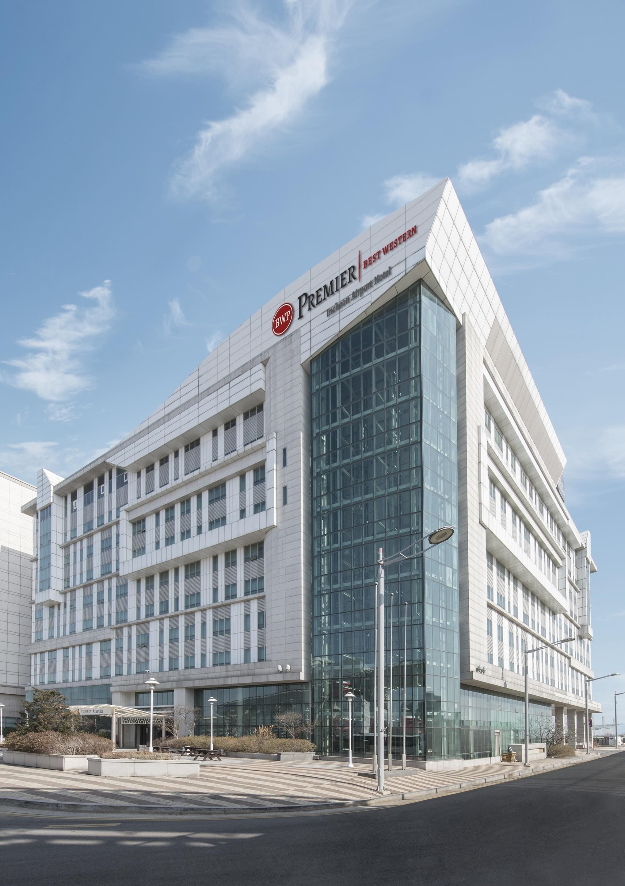 A modern hotel building with a prominent 'Premier' sign, large glass windows, and a clean, contemporary design.