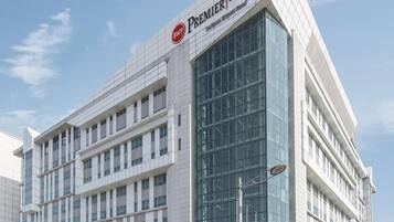 A modern hotel building with a prominent 'Premier' sign, large glass windows, and a clean, contemporary design.