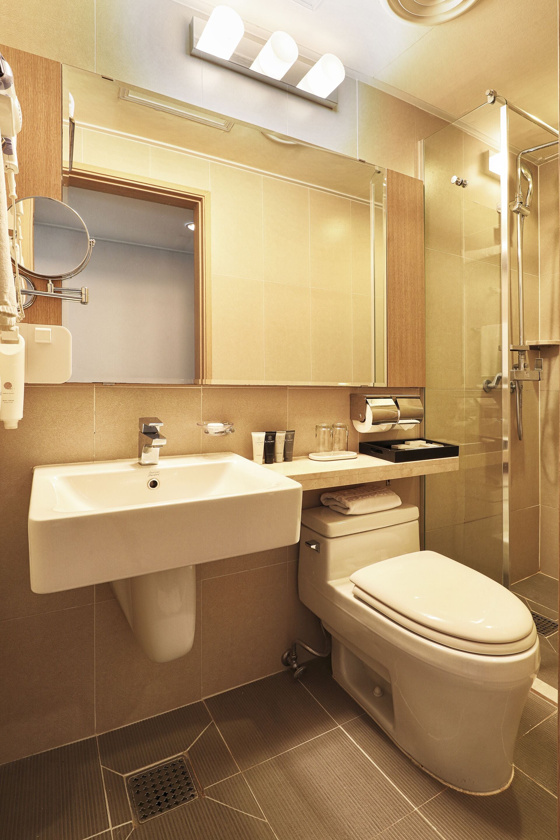 Un baño moderno con lavamanos, espejo, inodoro y ducha.
