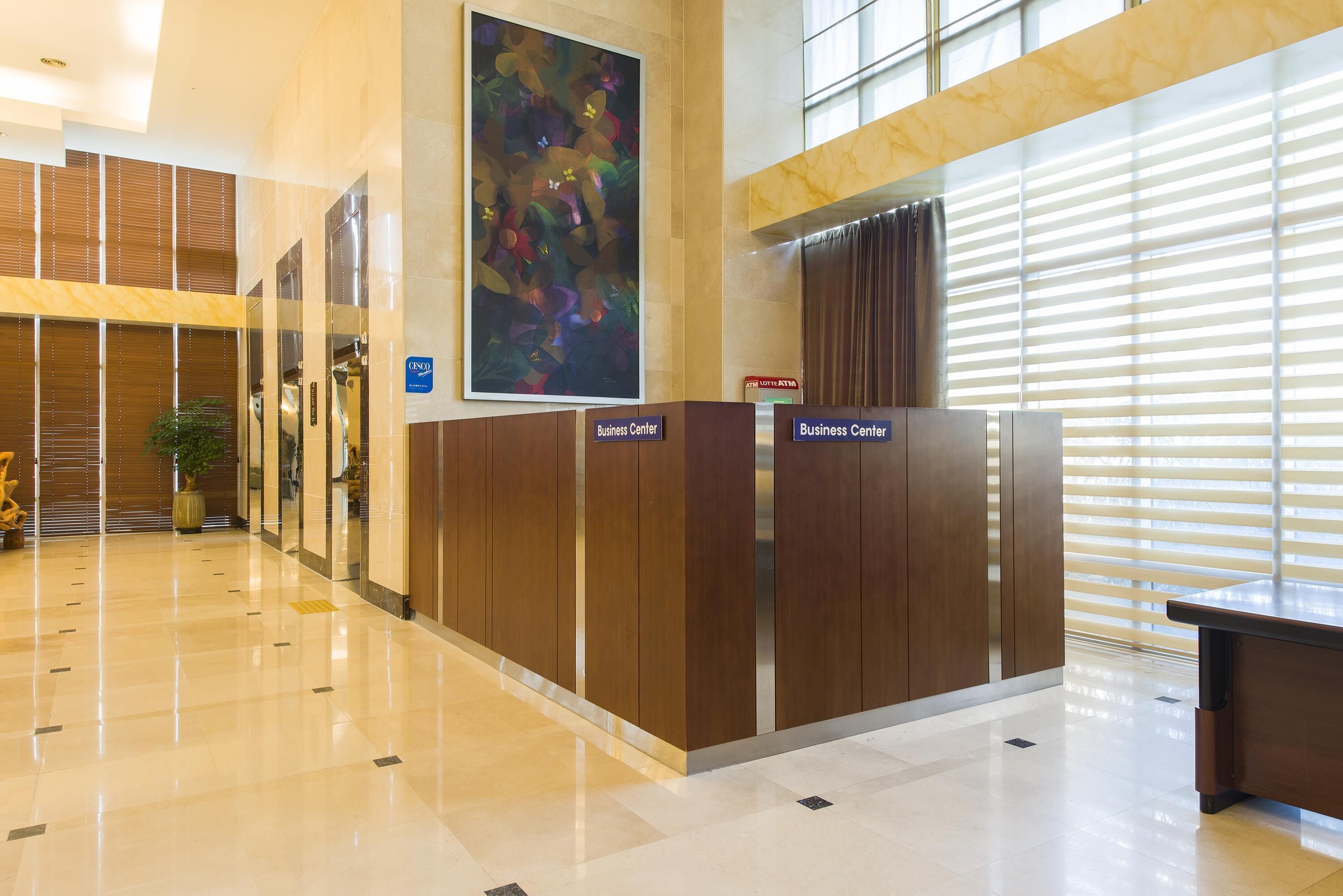 A modern business center with a polished marble floor, wooden paneling, and a large abstract painting.