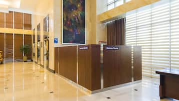 A modern business center with a polished marble floor, wooden paneling, and a large abstract painting.