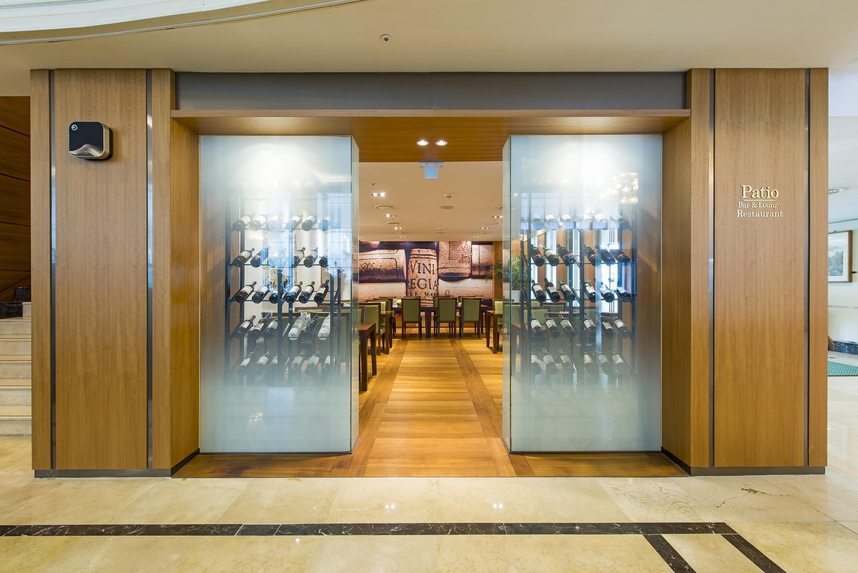 A hotel entrance with a wine cellar visible through frosted glass doors.