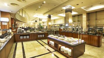 A hotel breakfast area with buffet counters, a reception desk, and a large mirror.