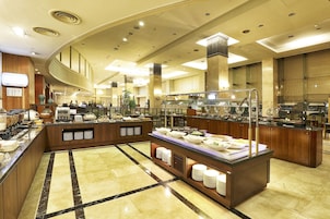A hotel breakfast area with buffet counters, a reception desk, and a large mirror.