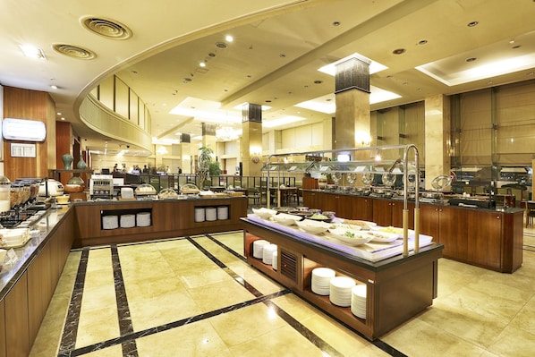 Un comedor de hotel con mostradores de buffet, una recepción y un espejo grande.