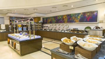 A buffet area with various food items and a large floral artwork on the wall.