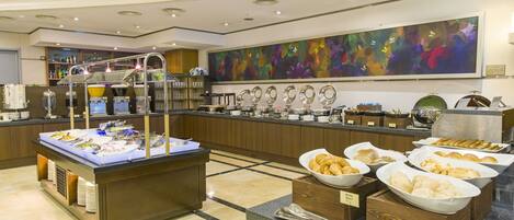 A buffet area with various food items and a large floral artwork on the wall.