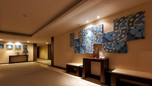 Eine großzügige Lobby mit modernem Design, inklusive einer großen Wandkunstinstallation und einer Rezeption.