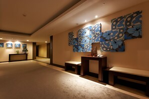 A spacious lobby with a modern design, featuring a large wall art installation and a reception desk.