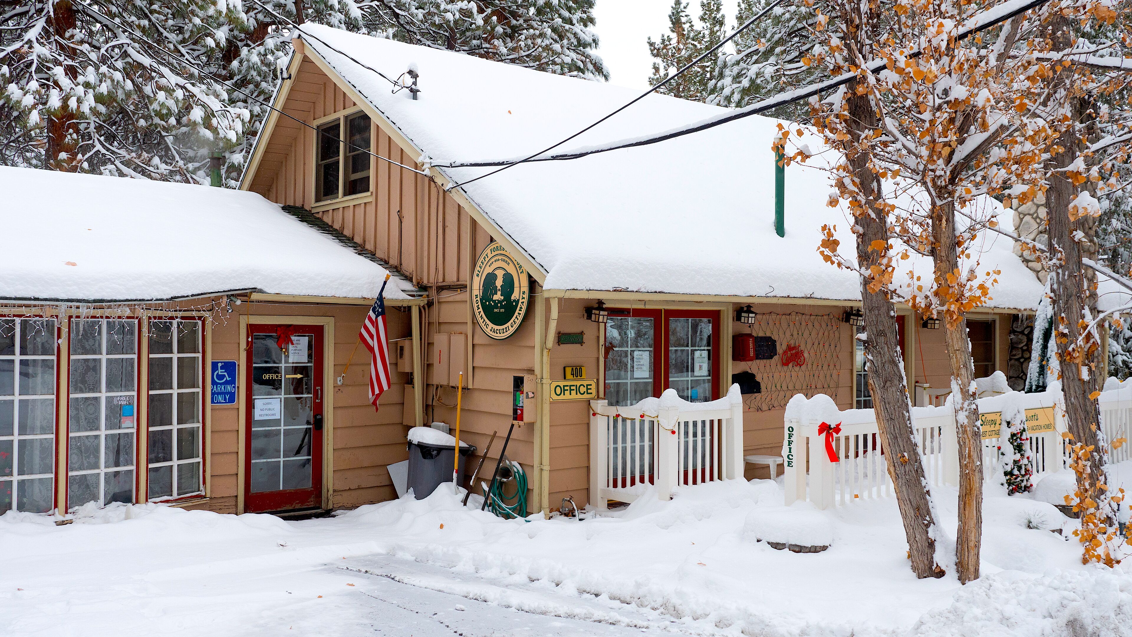 A wooden building with a red door, an American flag, and a sign indicating an office.