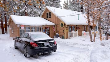 A snow-covered building with a car parked in front, a wooden exterior, and a sign indicating an office.
