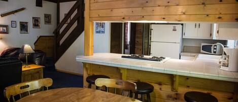 A cozy kitchen with wooden accents, a dining area with a round table and chairs, and a visible refrigerator.