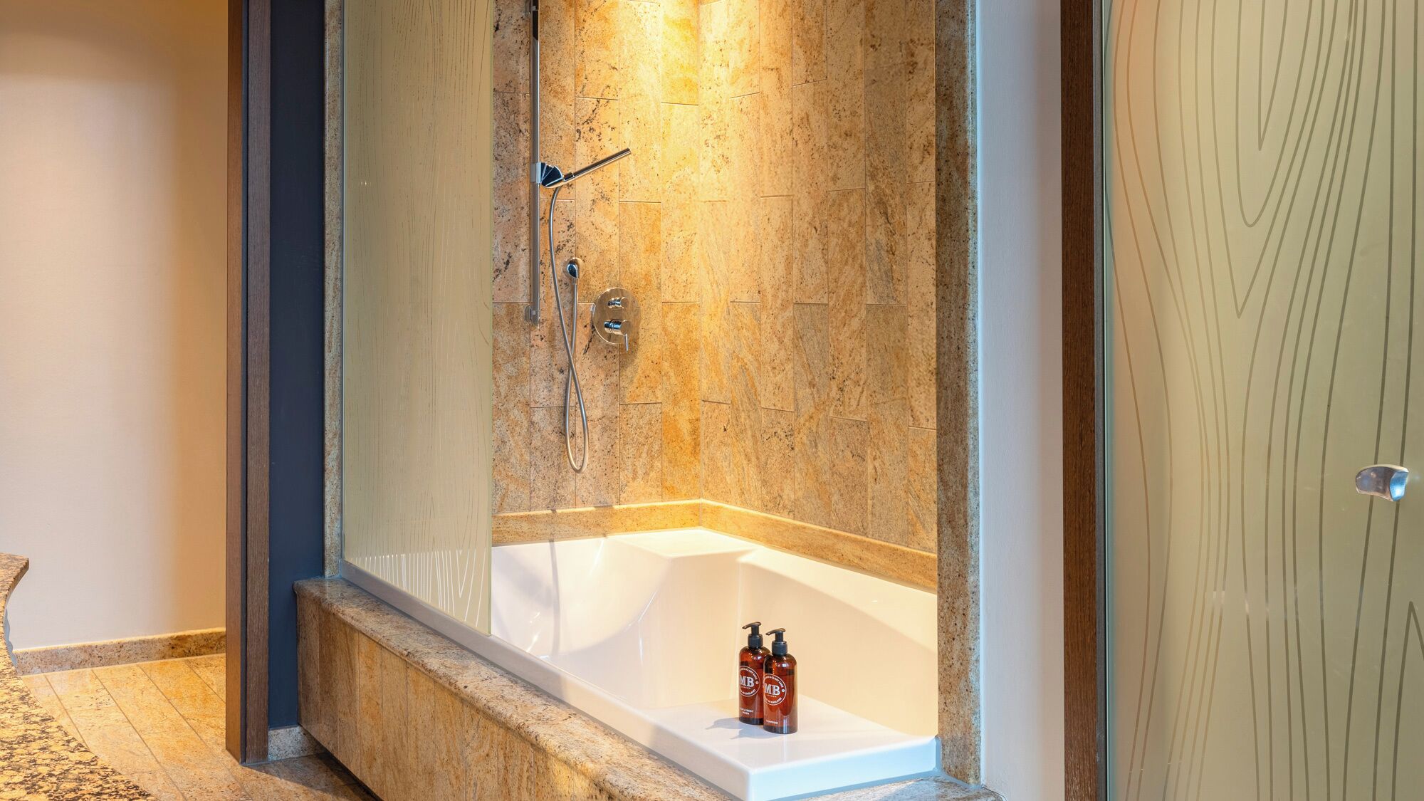 A modern bathroom with a freestanding bathtub, a shower area, and a marble-tiled wall.