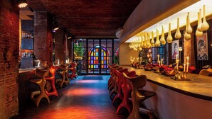 Eine Bar mit Backsteinwand, einer Theke und einer Sitzgelegenheit mit Stühlen.