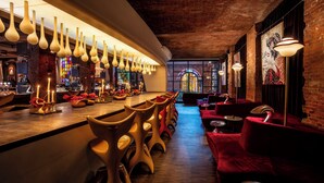 Eine Bar mit einer langen Theke, mehreren Barhocker und einer Sitzecke mit rot gepolsterten Stühlen.