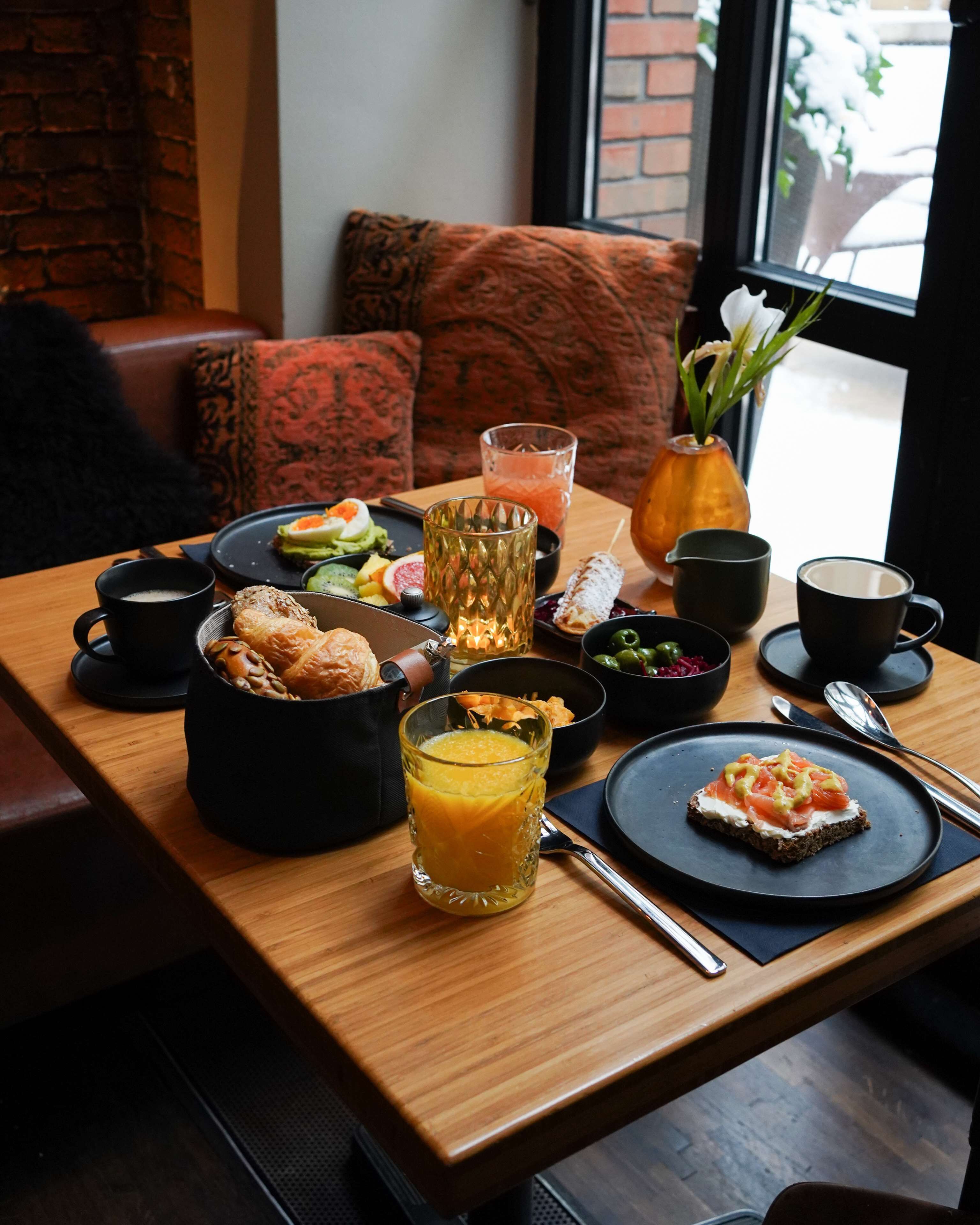 A breakfast table with various dishes, a glass of orange juice, and a cup of coffee.