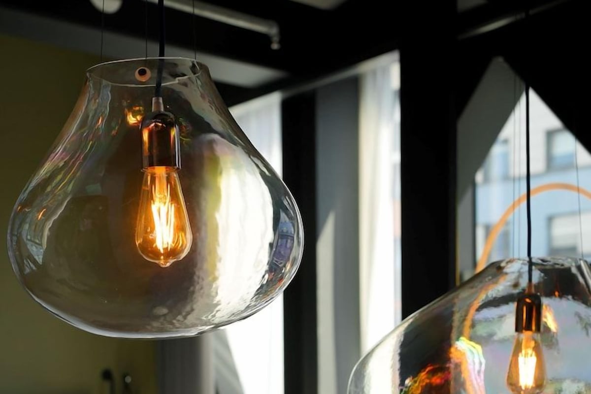 A room with a bed, a bedside table, and two hanging pendant lights with visible bulbs.