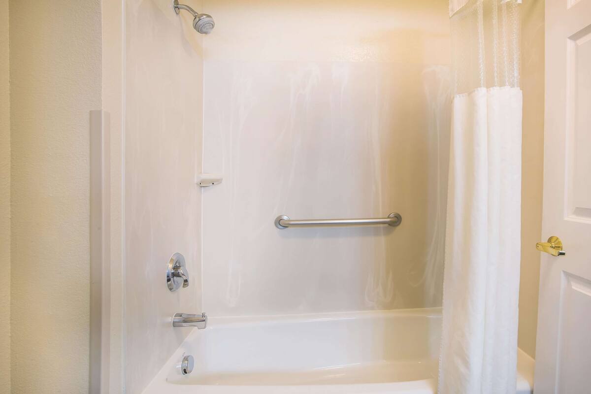 Ein helles Badezimmer mit einer Badewanne, einer Duschvorhang und einem Handtuchhalter.