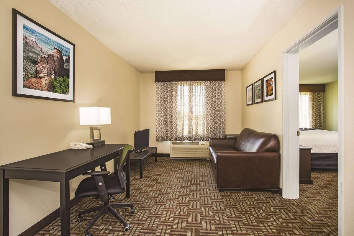 Ein Hotelzimmer mit Schreibtisch, Stuhl, Sofa und Bett.