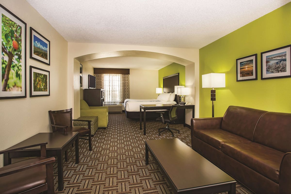 Ein Hotelzimmer mit Bett, Schreibtisch, Stuhl, Sofa und Fernseher.