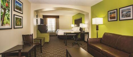 A hotel room with a bed, a desk, a chair, a couch, and a TV.