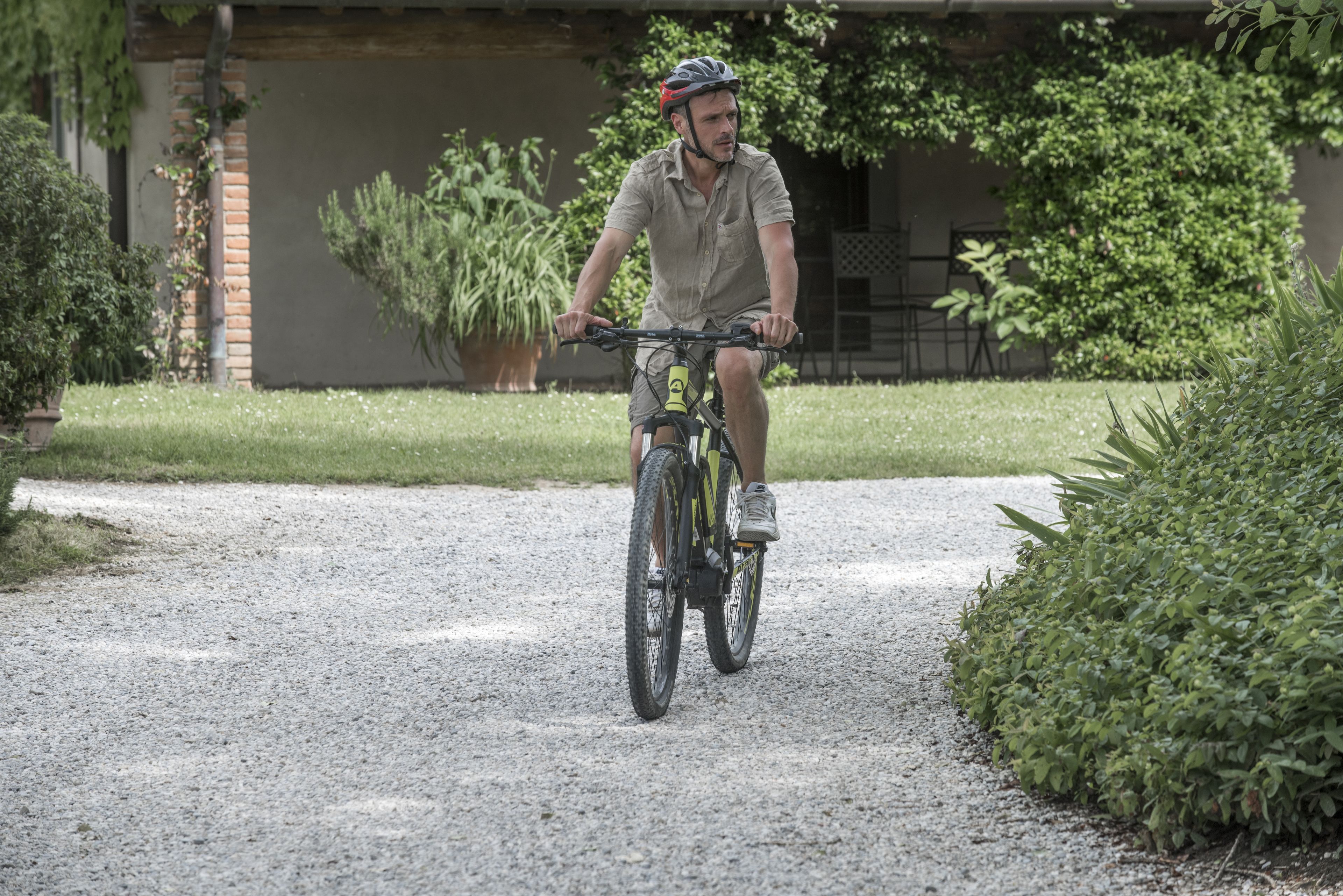 A person riding a bicycle on a gravel path.
